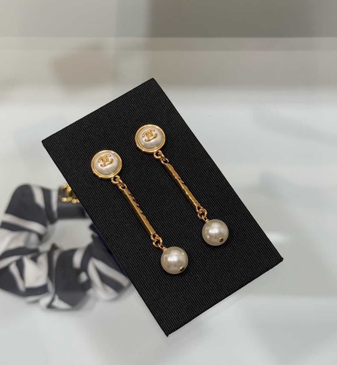 DreamStudio CHANEL gold-tone drop earrings featuring interlocking logo motifs and cream pearl accents on a black card.