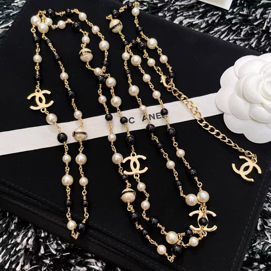 DreamStudio  long necklace featuring faux pearls, black beads, and gold-tone interlocking logo charms.