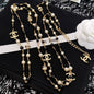 DreamStudio  long necklace featuring faux pearls, black beads, and gold-tone interlocking logo charms.