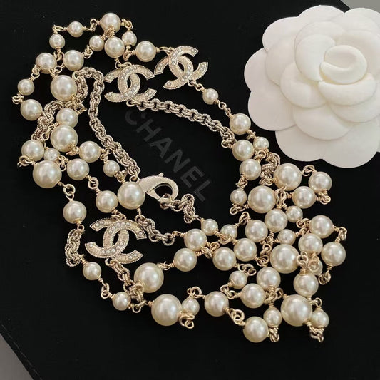 DreamStudio long pearl strand necklace with gold-tone chain links and crystal-embellished interlocking logo charms