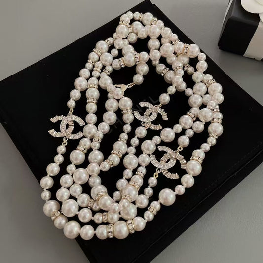 DreamStudio multi-strand pearl necklace with rhinestone spacers and crystal-embellished logo charms on a black display