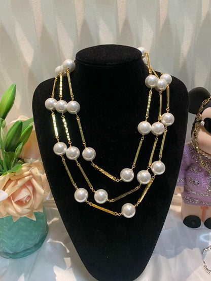 DreamStudio multi-strand statement necklace featuring lustrous white faux pearls and gold-toned metallic bar accents.
